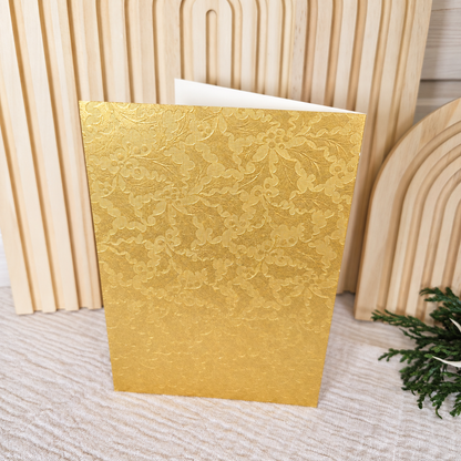Rückseite der Weihnachtskarte aus goldfarbenem Hammerschlagpapier mit Ilex-Muster