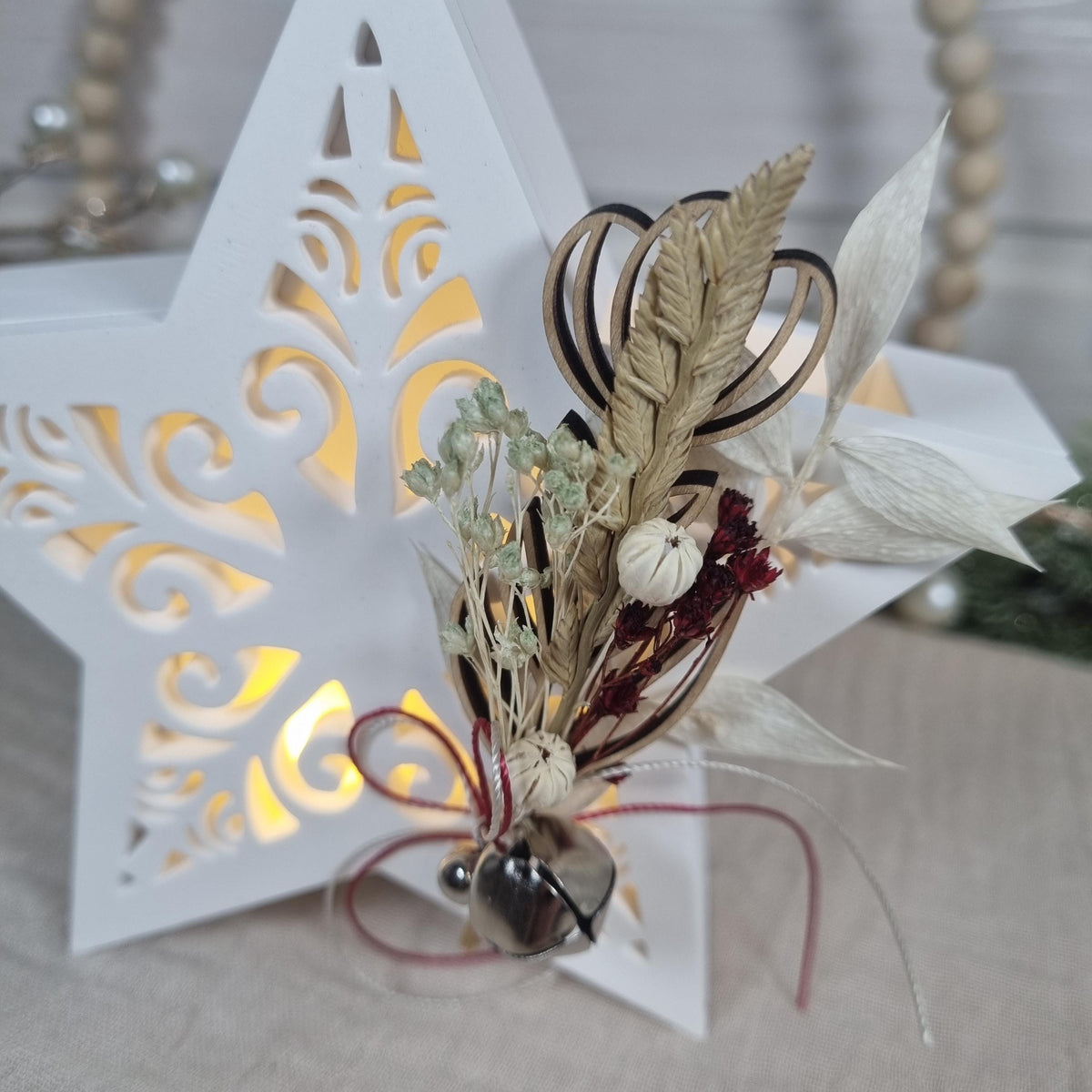 Detail des filigranen Sternmusters mit Transparentpapier, Trockenblumen und Glöckchen