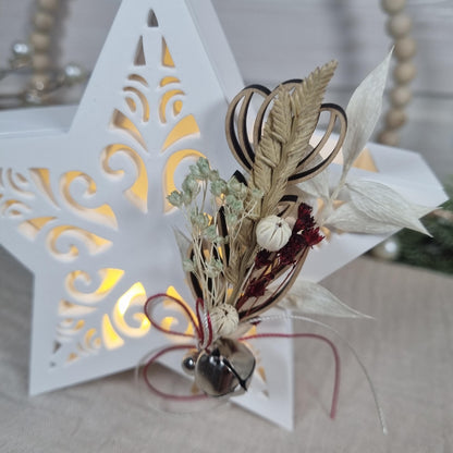 Detail des filigranen Sternmusters mit Transparentpapier, Trockenblumen und Glöckchen