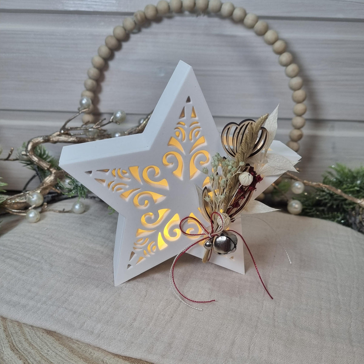 Beleuchteter Dekostern mit Trockenblumen und Glöckchen als Weihnachtsdekoration