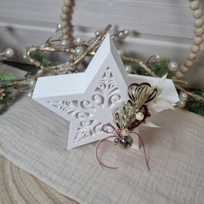 Weißer Gießkeramikstern mit Trockenblumenarrangement und kleinem Glöckchen