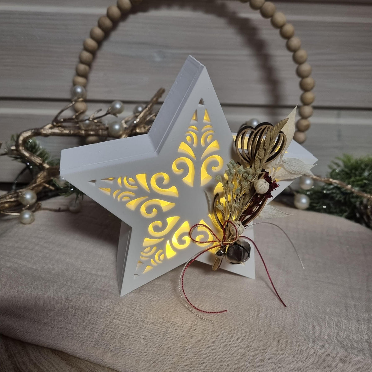 Beleuchteter Dekostern mit Trockenblumen und Glöckchen als Weihnachtsdekoration